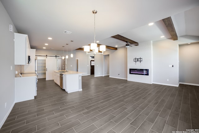 kitchen featuring sink, dark hardwood / wood-style flooring, a barn door, and an island with sink