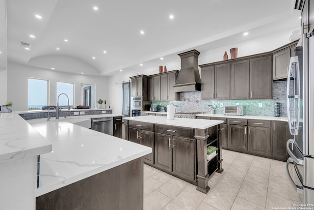 kitchen featuring appliances with stainless steel finishes, vaulted ceiling, custom exhaust hood, and light stone counters