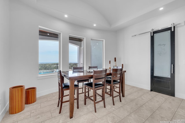 tiled dining room featuring vaulted ceiling and a barn door