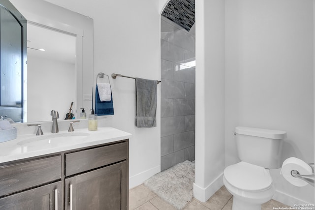 bathroom with tiled shower, vanity, toilet, and tile patterned flooring