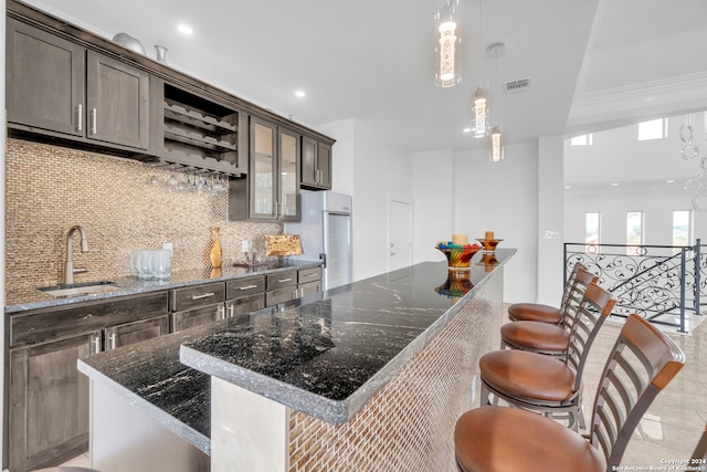 kitchen with dark stone countertops, a center island, tasteful backsplash, and sink