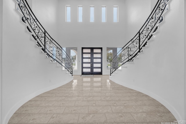 foyer featuring a high ceiling, light tile patterned floors, french doors, and a wealth of natural light