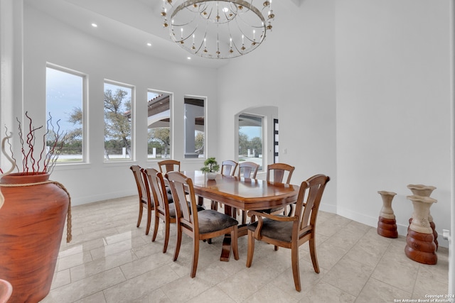 dining space with light tile patterned floors, a high ceiling, and a chandelier