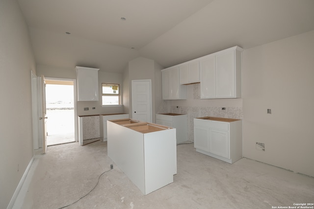 kitchen with a center island, white cabinetry, and lofted ceiling