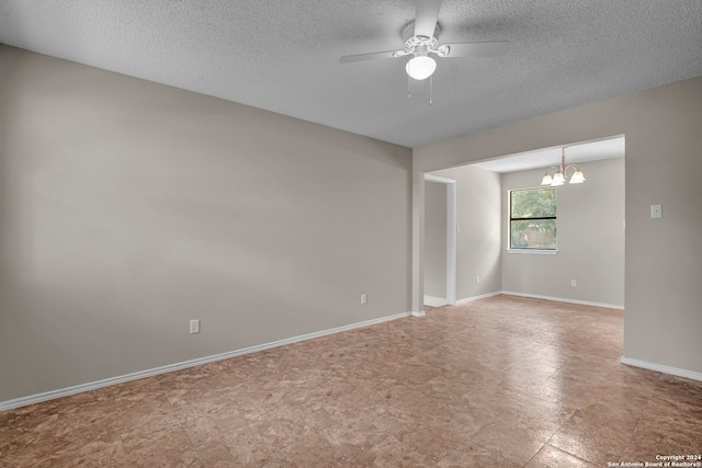 spare room featuring ceiling fan with notable chandelier and a textured ceiling