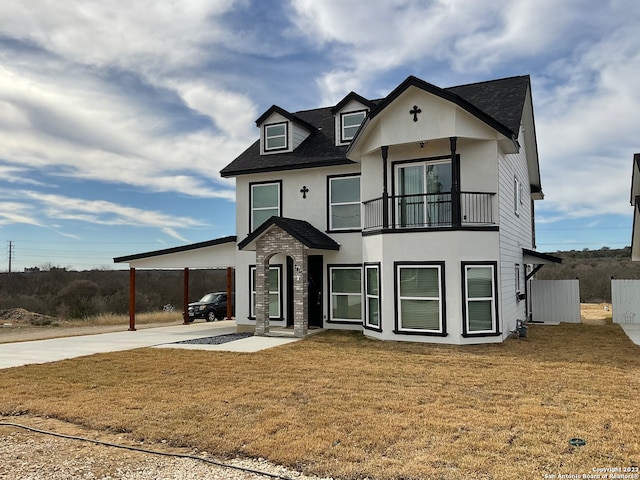 view of front of home with a balcony, a front lawn, and a carport