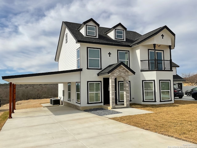 view of front of property with a balcony, a carport, central AC unit, and a front yard