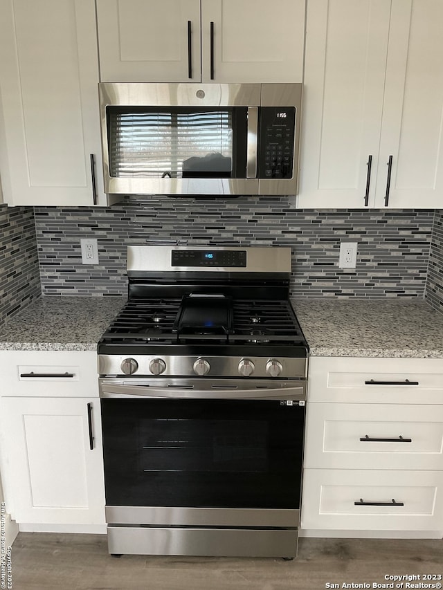 kitchen featuring white cabinetry, stainless steel appliances, and light stone counters