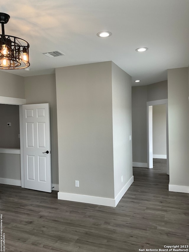 spare room featuring a notable chandelier and dark wood-type flooring