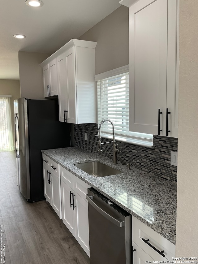 kitchen featuring sink, white cabinetry, decorative backsplash, stainless steel appliances, and hardwood / wood-style floors