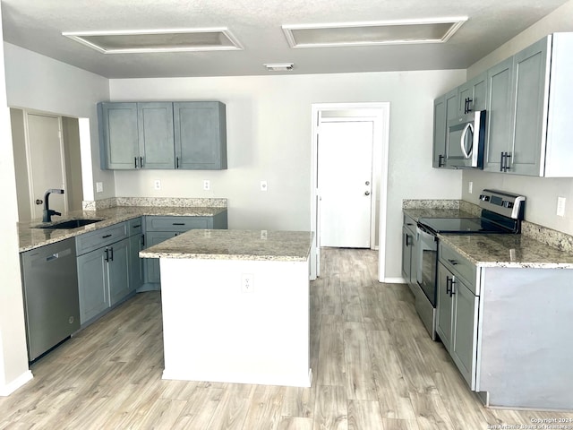 kitchen with appliances with stainless steel finishes, gray cabinets, a textured ceiling, light hardwood / wood-style flooring, and sink