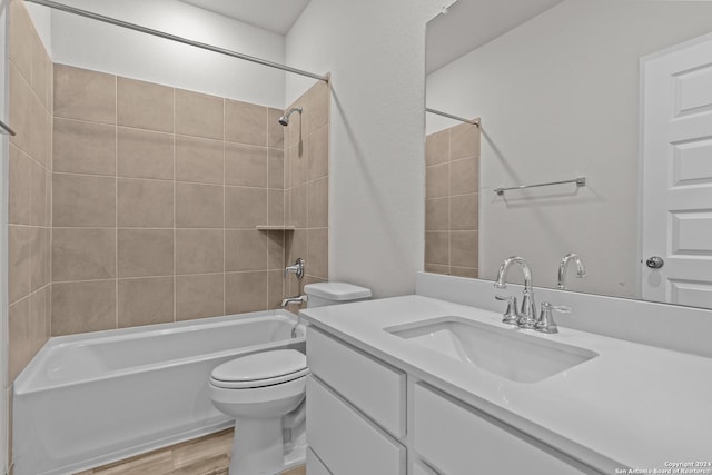 full bathroom featuring hardwood / wood-style floors, vanity, tiled shower / bath combo, and toilet