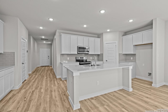 kitchen featuring sink, stainless steel appliances, light hardwood / wood-style flooring, a center island with sink, and white cabinets