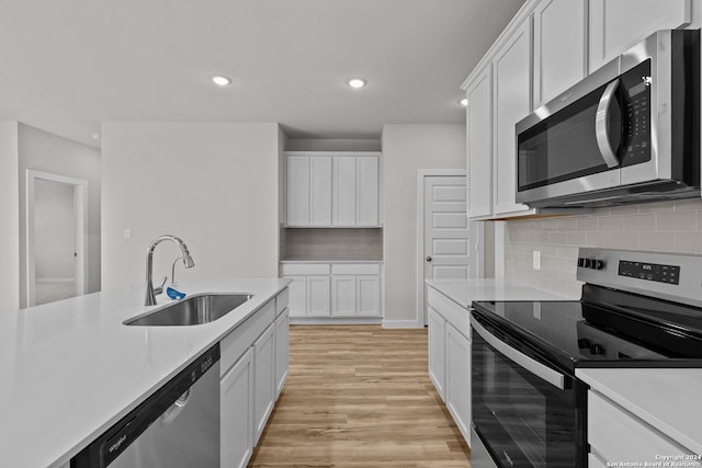 kitchen featuring white cabinetry, sink, appliances with stainless steel finishes, and light hardwood / wood-style flooring