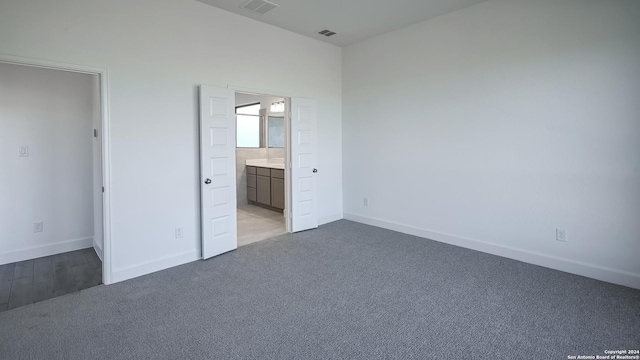 unfurnished bedroom featuring light carpet and connected bathroom