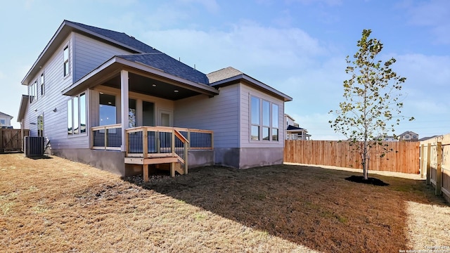 rear view of property featuring a lawn and central air condition unit