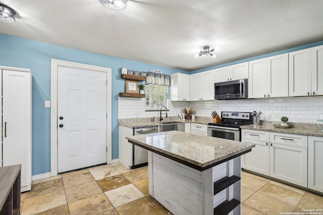 kitchen with decorative backsplash, white cabinetry, light stone countertops, stainless steel appliances, and sink