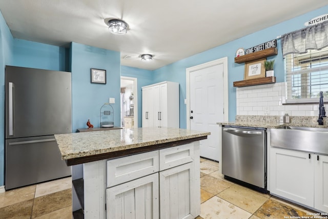 kitchen featuring a center island, sink, white cabinets, stainless steel appliances, and backsplash