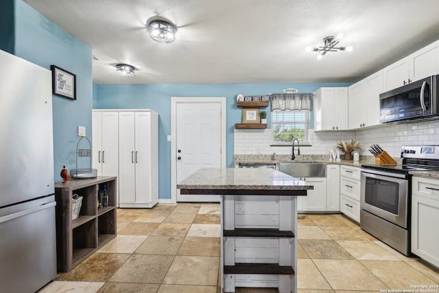 kitchen featuring sink, white cabinetry, a kitchen island, decorative backsplash, and stainless steel appliances