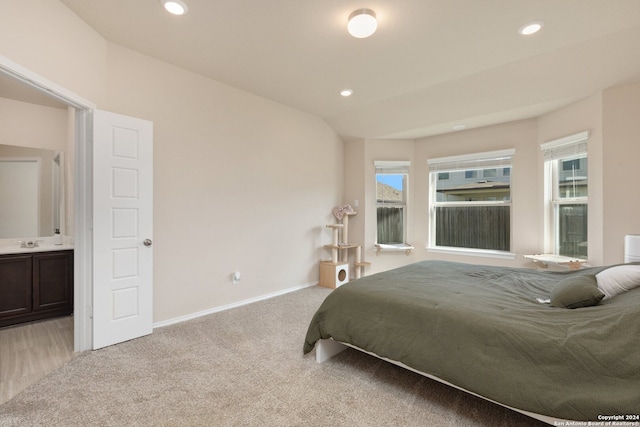 carpeted bedroom featuring connected bathroom, sink, and multiple windows