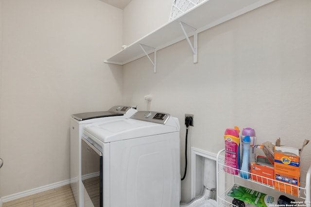 laundry area with washing machine and clothes dryer and light wood-type flooring