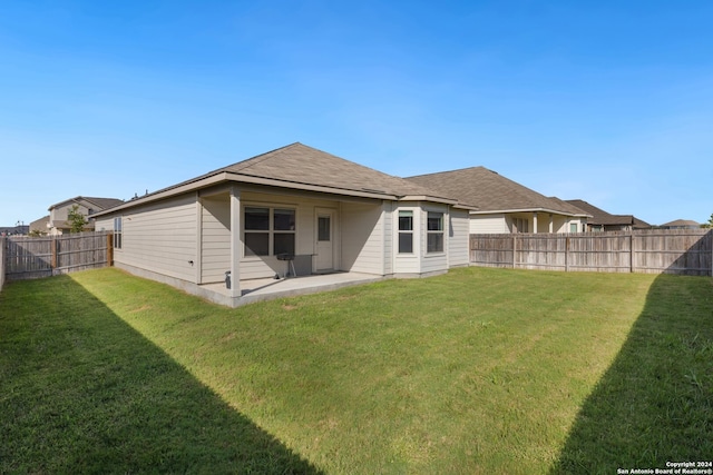 rear view of house featuring a lawn and a patio