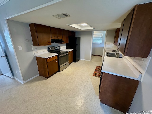 kitchen with black fridge, sink, decorative backsplash, a skylight, and stainless steel range with electric stovetop