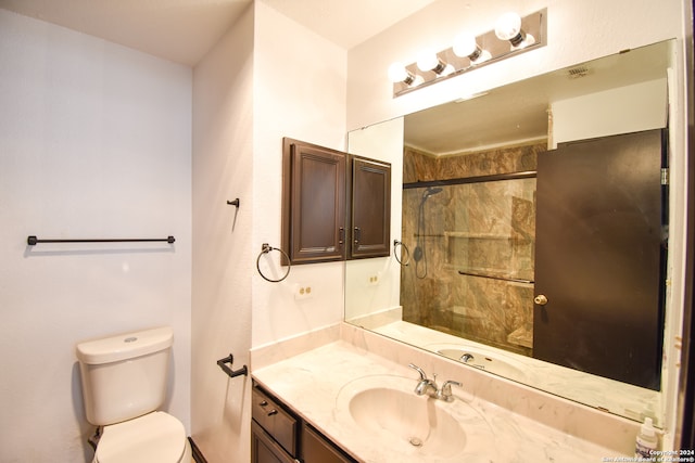 bathroom with vanity, toilet, and a shower with door