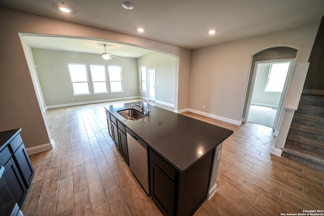 kitchen with an island with sink, ceiling fan, light hardwood / wood-style flooring, stainless steel dishwasher, and sink