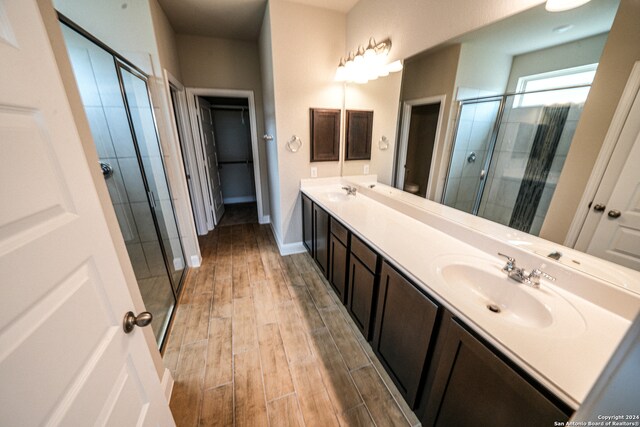 bathroom featuring a shower with shower door, hardwood / wood-style flooring, and vanity