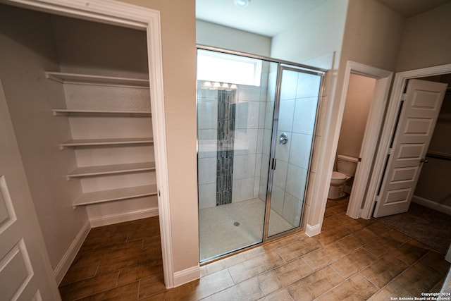 bathroom with a shower with shower door and toilet