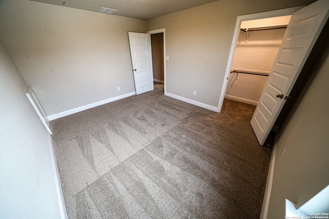 unfurnished bedroom with carpet, a walk in closet, and a closet