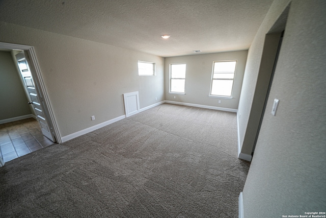 empty room featuring a textured ceiling and light carpet