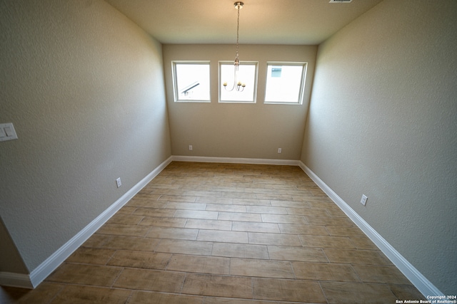 empty room featuring a chandelier and hardwood / wood-style flooring