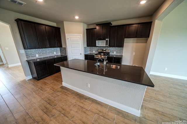 kitchen featuring light hardwood / wood-style flooring, stainless steel appliances, a center island with sink, and sink