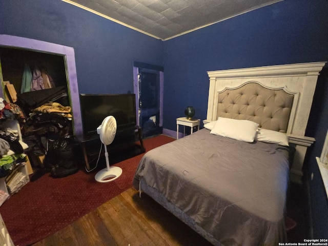 bedroom with dark wood-type flooring and crown molding