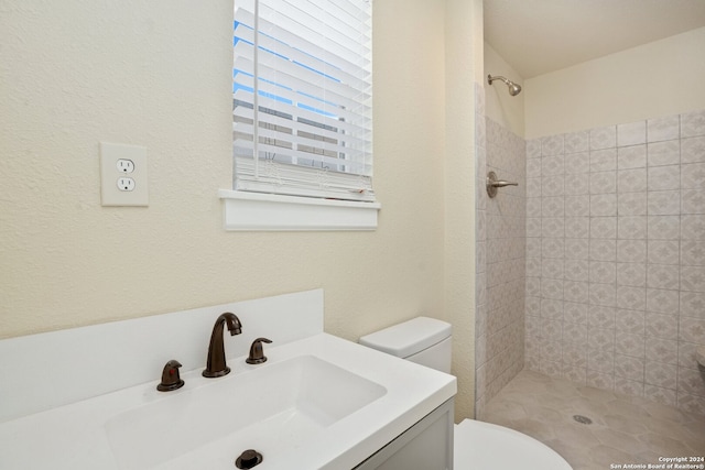 bathroom featuring tiled shower, vanity, and toilet