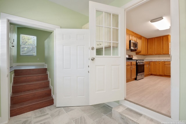 interior space featuring lofted ceiling, light hardwood / wood-style floors, and appliances with stainless steel finishes