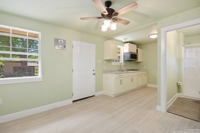 kitchen featuring white cabinets, stainless steel appliances, light wood-type flooring, ceiling fan, and sink