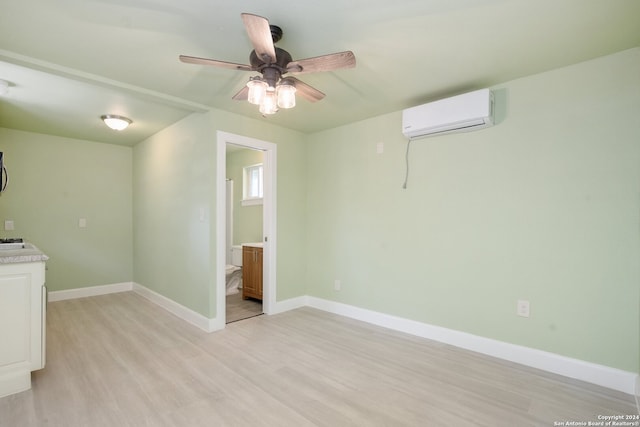 spare room with light wood-type flooring, ceiling fan, and a wall mounted air conditioner