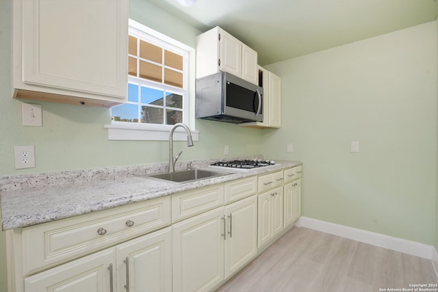 kitchen featuring light wood-type flooring, sink, stainless steel appliances, and light stone counters