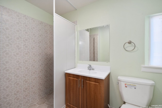 bathroom featuring vanity, plenty of natural light, toilet, and tiled shower