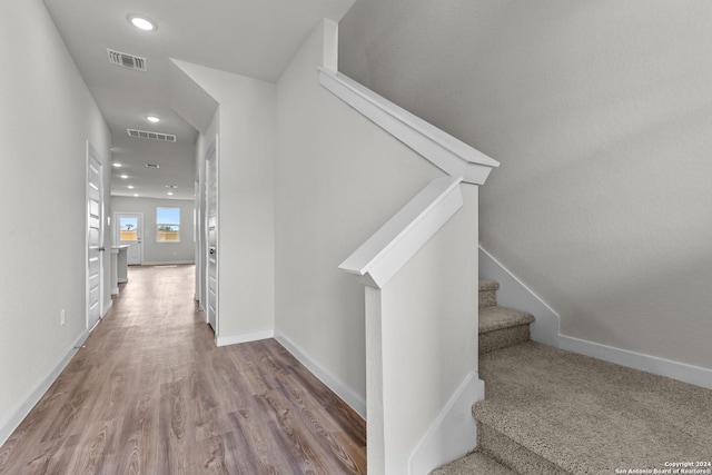 hallway with wood finished floors, stairway, recessed lighting, and visible vents