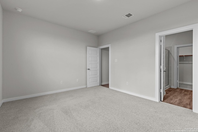 unfurnished bedroom featuring a spacious closet, visible vents, baseboards, and carpet