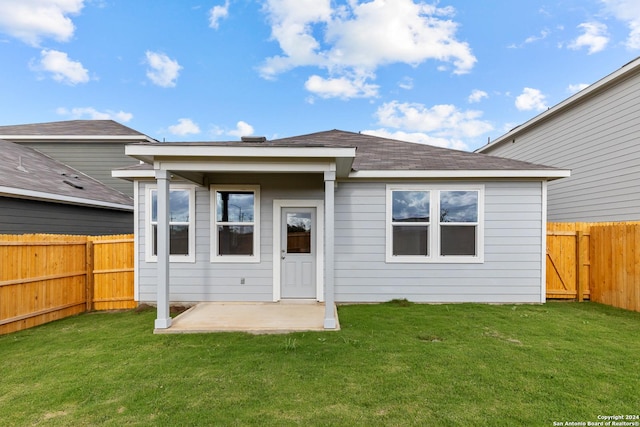 rear view of property featuring a yard, a patio, roof with shingles, and a fenced backyard