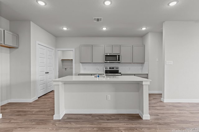 kitchen with stainless steel appliances, gray cabinetry, light countertops, and visible vents
