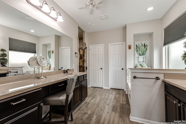 bathroom with wood-type flooring, ceiling fan, a bath, and vanity