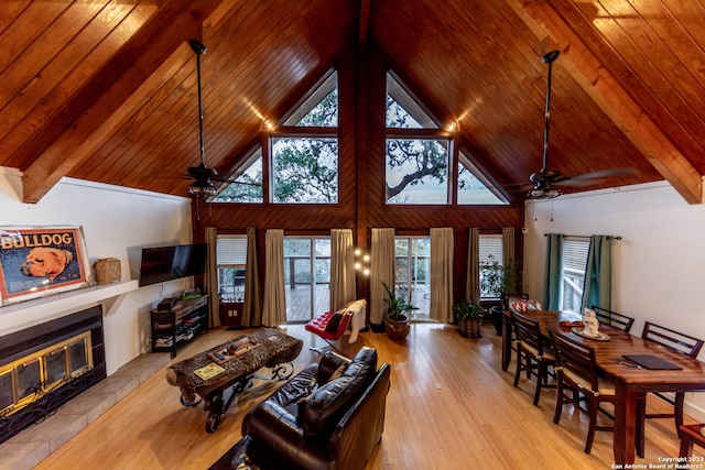 living room with a tile fireplace, wood ceiling, ceiling fan, beam ceiling, and light hardwood / wood-style flooring