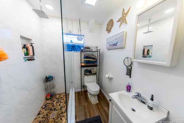 bathroom featuring vanity, wood-type flooring, toilet, and tiled shower