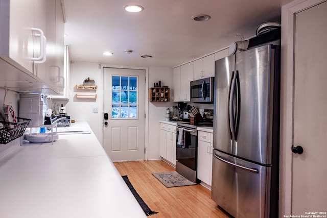 kitchen featuring white cabinetry, stainless steel appliances, sink, and light wood-type flooring